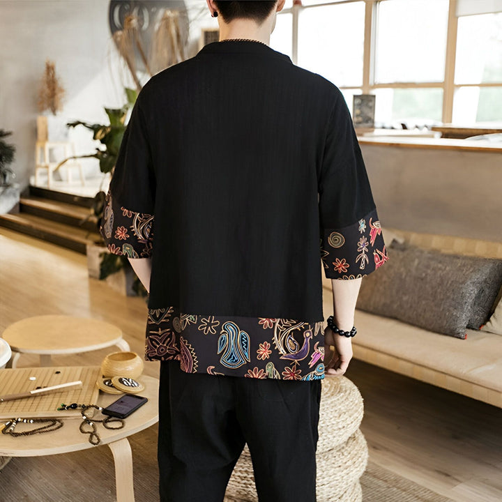 Dos d'un homme portant un kimono noir avec des motifs floraux et des oiseaux stylisés sur les manches et le bas. Vêtements de style japonais disponibles à l'achat.