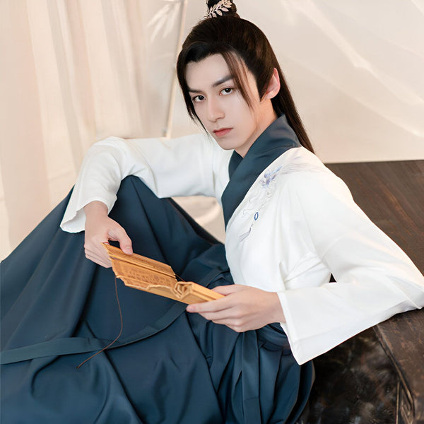Homme asiatique portant un kimono traditionnel bleu et blanc, tenant un éventail. Vêtements japonais élégants, idéal pour un style unique. Découvrez notre collection de kimonos.