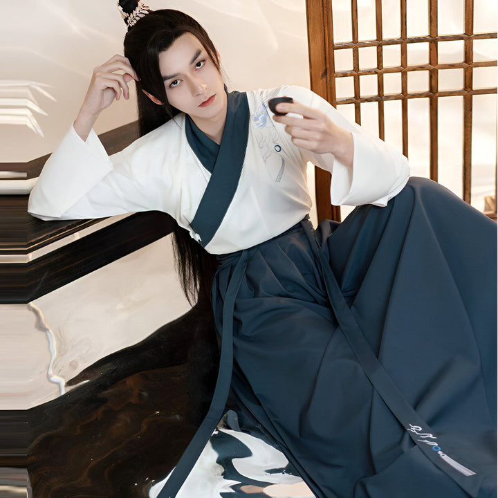Homme portant un kimono blanc et bleu marine, style asiatique traditionnel. Vente de kimonos authentiques en ligne. Détails brodés et élégance.
