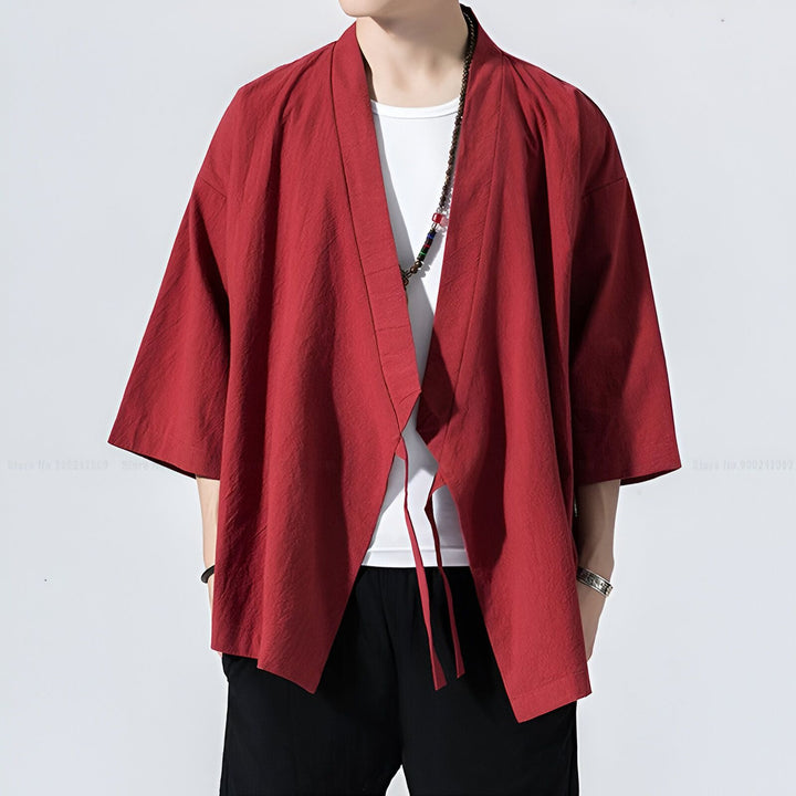 Homme portant un kimono rouge ample avec un t-shirt blanc et un pantalon noir. Veste kimono ouverte à manches courtes, style japonais moderne. Vêtements kimono de notre boutique en ligne.