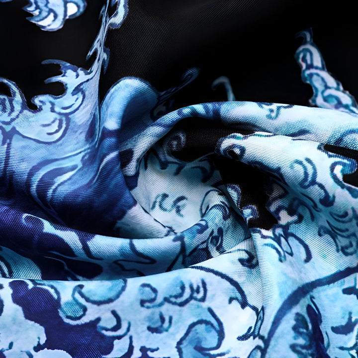 Gros plan sur le tissu d'un kimono avec un motif de vagues japonaises bleues et blanches sur fond noir. Découvrez nos kimonos uniques.