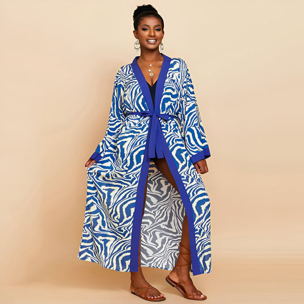Femme portant un kimono long bleu et blanc à motifs zébrés, avec une ceinture bleue. Parfait pour la plage ou comme vêtement d'intérieur élégant. Découvrez notre collection de kimonos uniques.