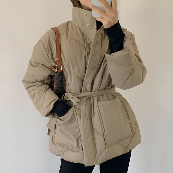 Femme portant un manteau kimono matelassé beige avec une ceinture et un sac à main. Mode kimono d'hiver.