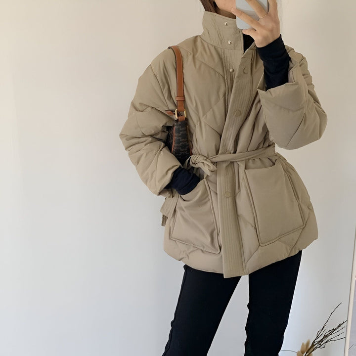Femme portant un kimono matelassé beige avec ceinture, col montant et une sacoche marron. Vêtements d'extérieur d'inspiration japonaise.