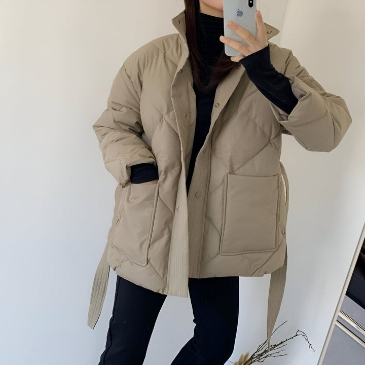 Femme portant un kimono matelassé beige avec ceinture. Vêtement d'extérieur à losanges avec poches. Mode kimono d'hiver.