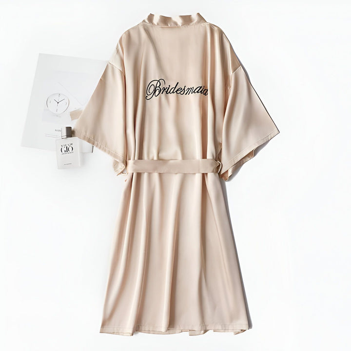 Kimono beige avec l'inscription "Bridesmaid" brodée. Peignoir soyeux pour demoiselle d'honneur, vêtement d'intérieur confortable et élégant. Idéal comme cadeau ou pour se préparer le jour du mariage.