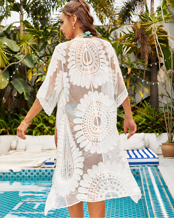 Femme portant un kimono blanc en dentelle à motifs floraux près d'une piscine. Kimono de plage élégant et léger, parfait pour l'été. Collection de kimonos uniques.