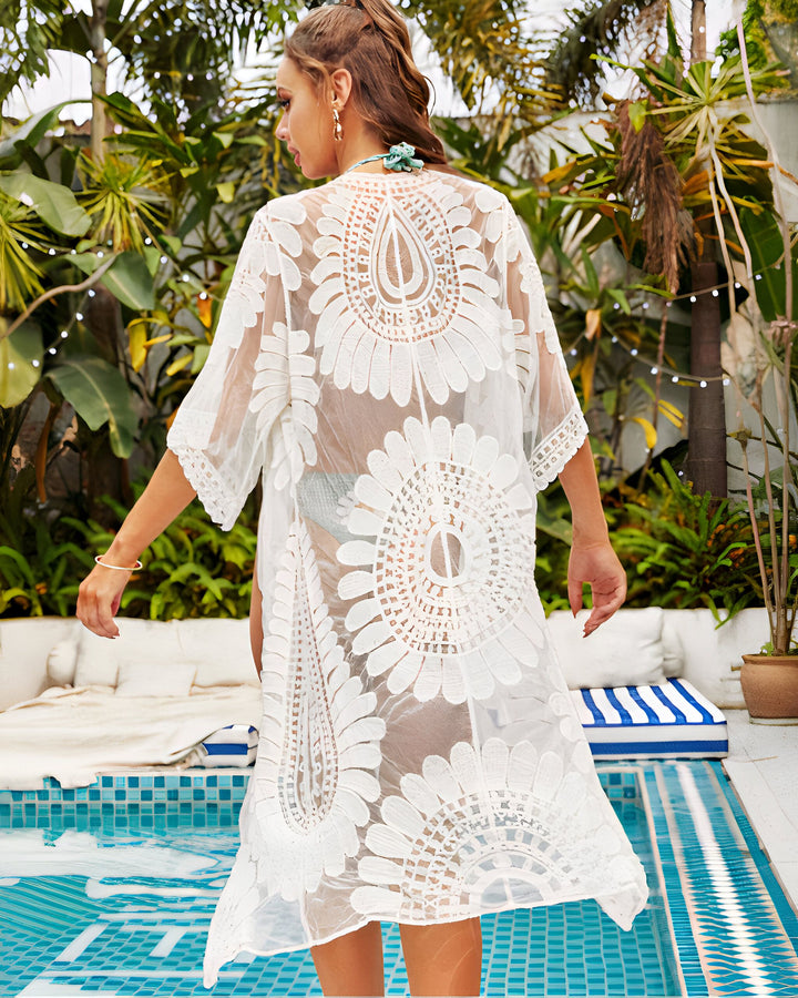 Femme portant un kimono blanc en dentelle à motifs floraux près d'une piscine. Kimono de plage élégant et léger, parfait pour l'été. Collection de kimonos uniques.