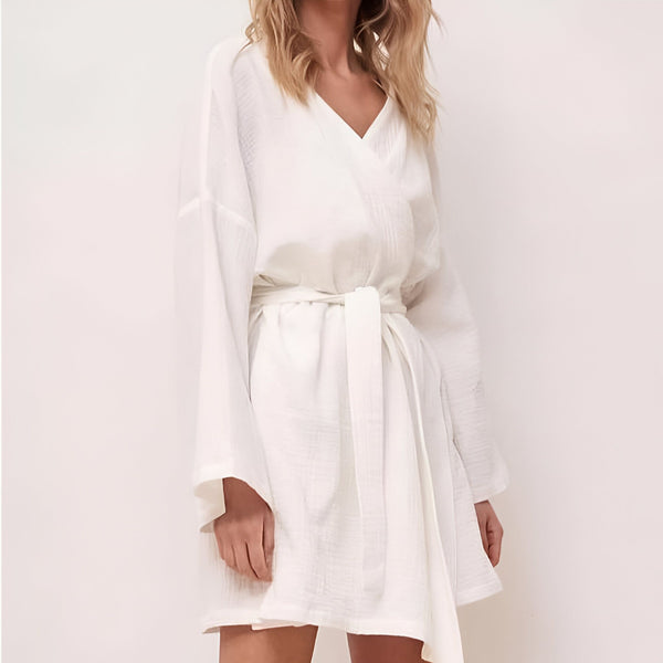 Femme portant un kimono blanc court en coton, avec ceinture nouée. Vêtement d'intérieur confortable et élégant. Disponible dans notre collection de kimonos.