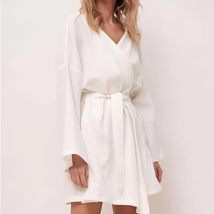 Femme portant un kimono blanc court en coton, avec ceinture nouée. Vêtement d'intérieur confortable et élégant. Disponible dans notre collection de kimonos.