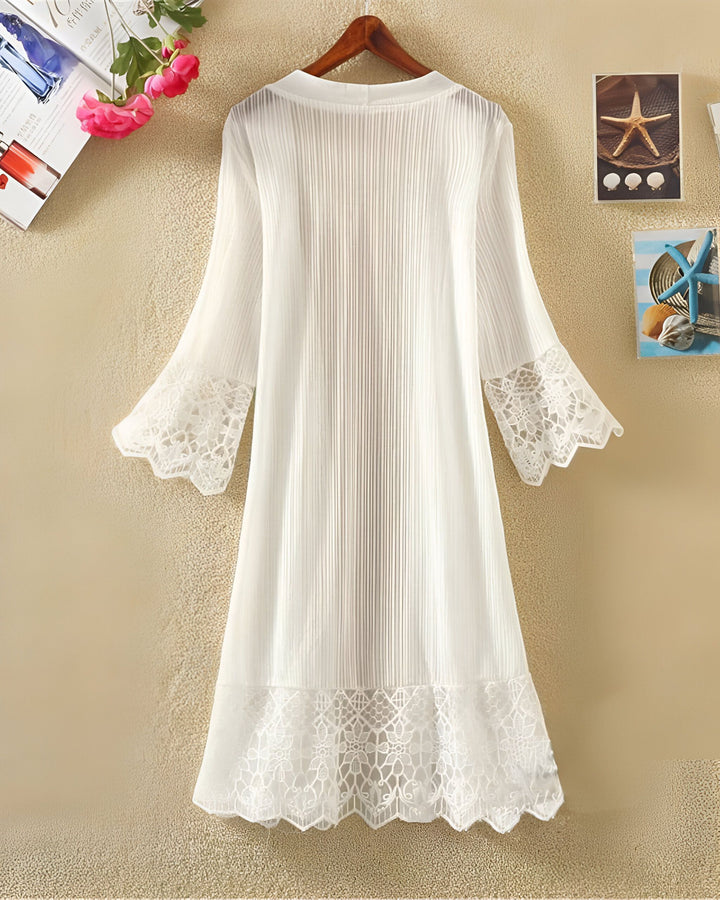 Kimono blanc léger avec dentelle délicate, suspendu à un cintre. Idéal pour compléter votre garde-robe d'été. Découvrez notre collection de kimonos uniques.