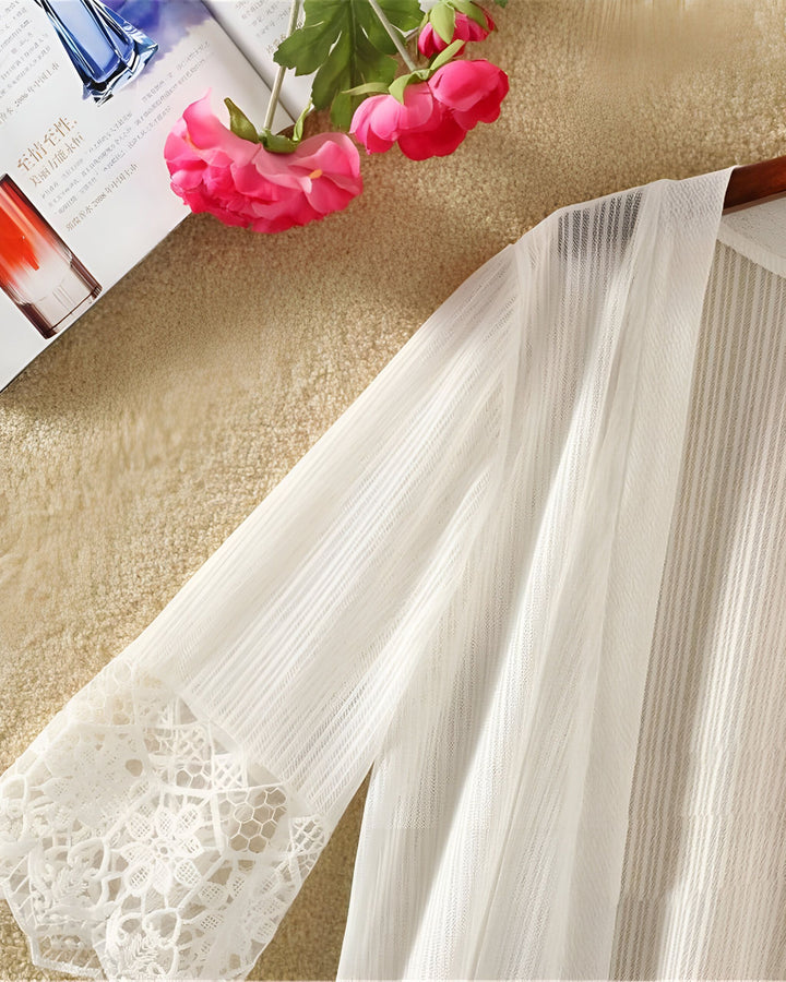 Kimono blanc léger en mousseline avec détails en dentelle aux manches. Idéal pour une superposition élégante. Découvrez notre collection de kimonos uniques en ligne.
