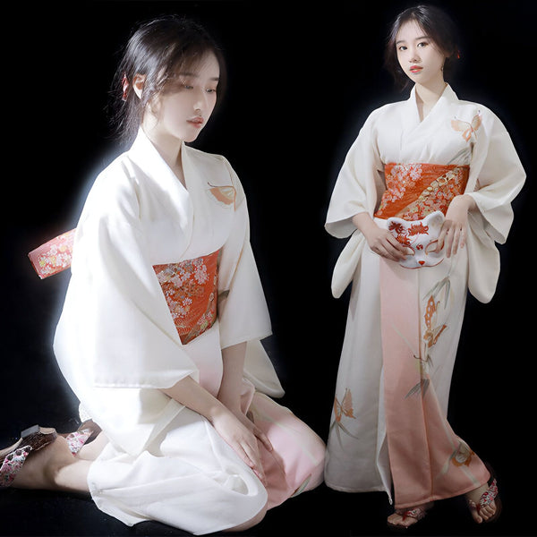 Deux femmes portant des kimonos blancs traditionnels avec des motifs floraux et des ceintures obi orange. L'une tient un masque de renard. Kimonos japonais élégants à vendre.