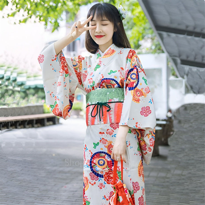 Jeune femme souriante portant un kimono blanc fleuri avec obi vert. Vêtements traditionnels japonais. Découvrez notre collection de kimonos.