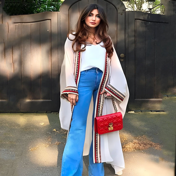 Femme élégante portant un kimono blanc avec motifs rouges et noirs. Style décontracté avec jean bleu et sac rouge. Collection de kimonos tendance.