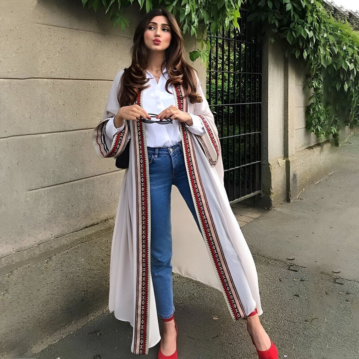 Femme portant un kimono long et élégant avec des motifs géométriques rouges et blancs. Elle porte un jean, une chemise blanche et des chaussures rouges. Kimonos de haute qualité disponibles à l'achat.