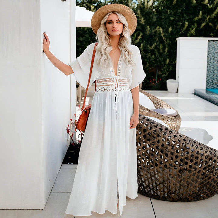 Femme portant un kimono blanc, chapeau de paille et sac à bandoulière dans un cadre extérieur élégant. Découvrez nos kimonos tendance pour un look estival chic.