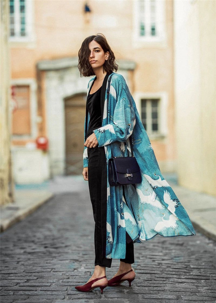 Femme portant un kimono bleu à motifs de grues blanches, pantalon noir, talons rouges et sac bandoulière. Élégance et style. Vêtements d'extérieur, mode femme.