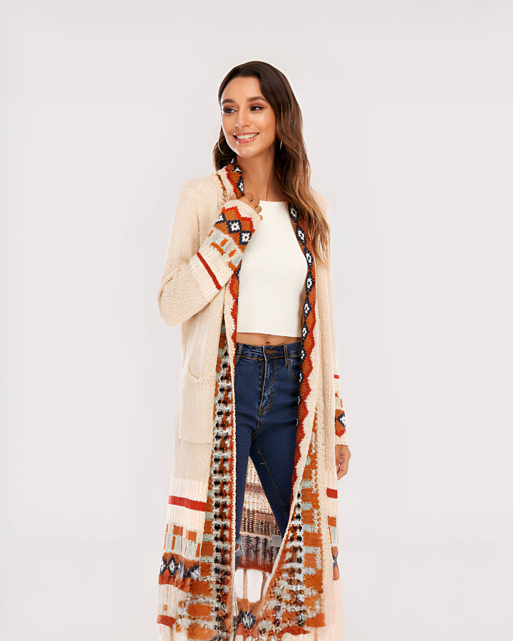 Femme souriante portant un long kimono beige à motifs ethniques, jeans et top blanc. Vêtements kimono de notre collection.
