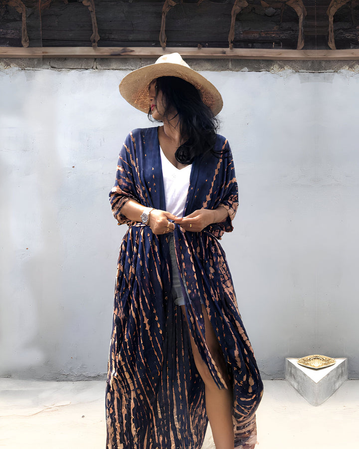 Femme portant un long kimono bleu marine à motifs, chapeau de paille. Vêtements d'été élégants, vente de kimonos en ligne. Mode bohème chic, look décontracté et tendance.