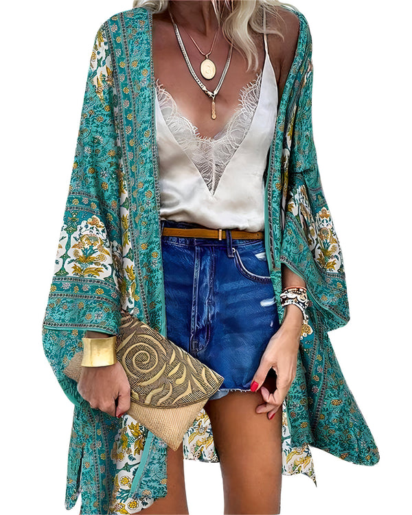 Femme portant un kimono turquoise à motifs floraux, un short en jean et un débardeur en dentelle. Elle tient une pochette dorée. Kimono tendance à acheter en ligne.