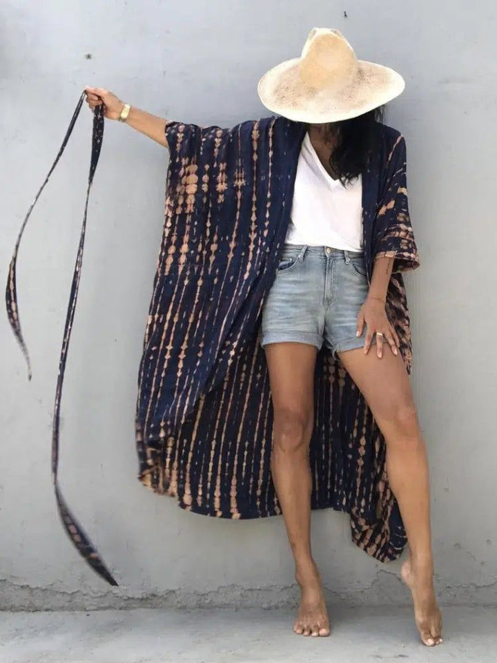 Femme portant un kimono indigo tie-dye avec un chapeau. Vêtements de plage de style bohème chic. Kimonos pour femmes de notre collection.