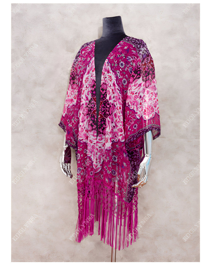 Kimono fleuri rose et blanc à franges fuchsia. Vêtement ample à motifs floraux, idéal pour un look bohème chic. Découvrez notre collection de kimonos.