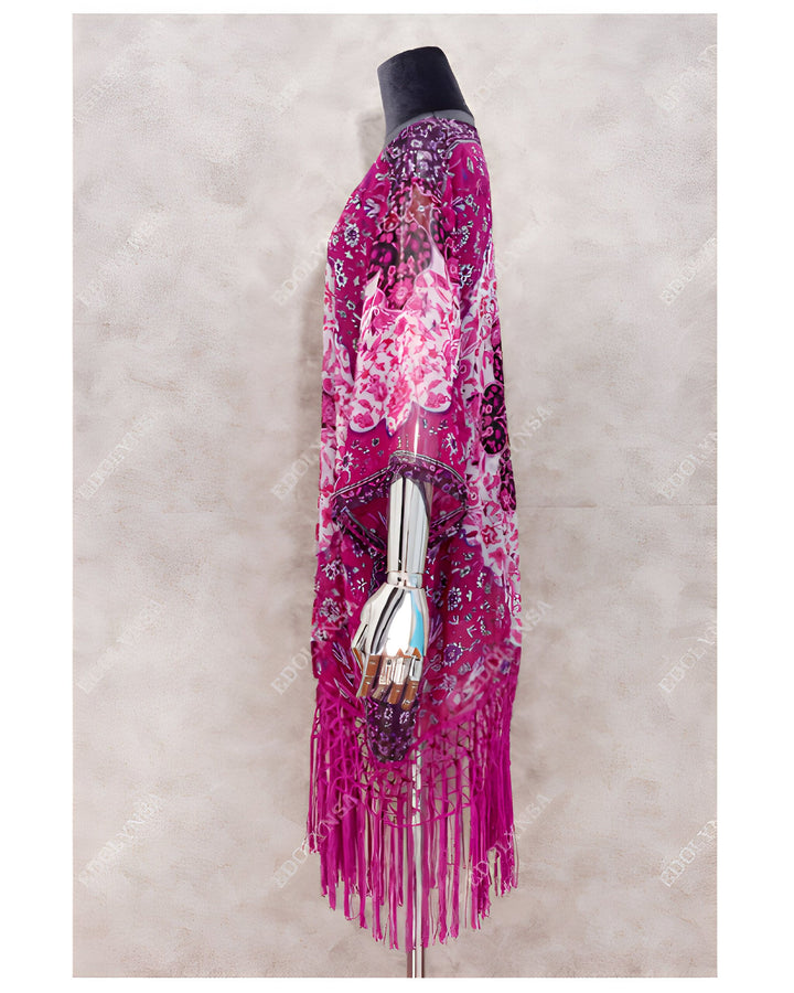 Kimono rose vif avec motifs et franges, présenté sur un mannequin. Idéal pour un look bohème chic.