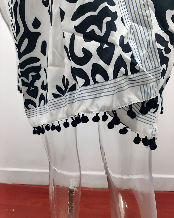 Détail d'un kimono blanc à motifs et pompons noirs. Vêtement d'intérieur confortable et élégant. Découvrez notre collection de kimonos.