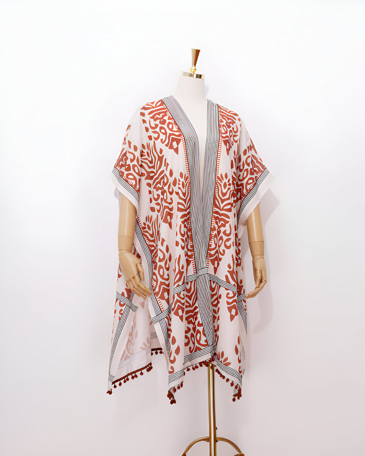 Kimono femme blanc avec motifs rouille et bordures à rayures noires, orné de pompons marron. Vêtement léger et élégant, parfait pour l'été. Collection kimonos.
