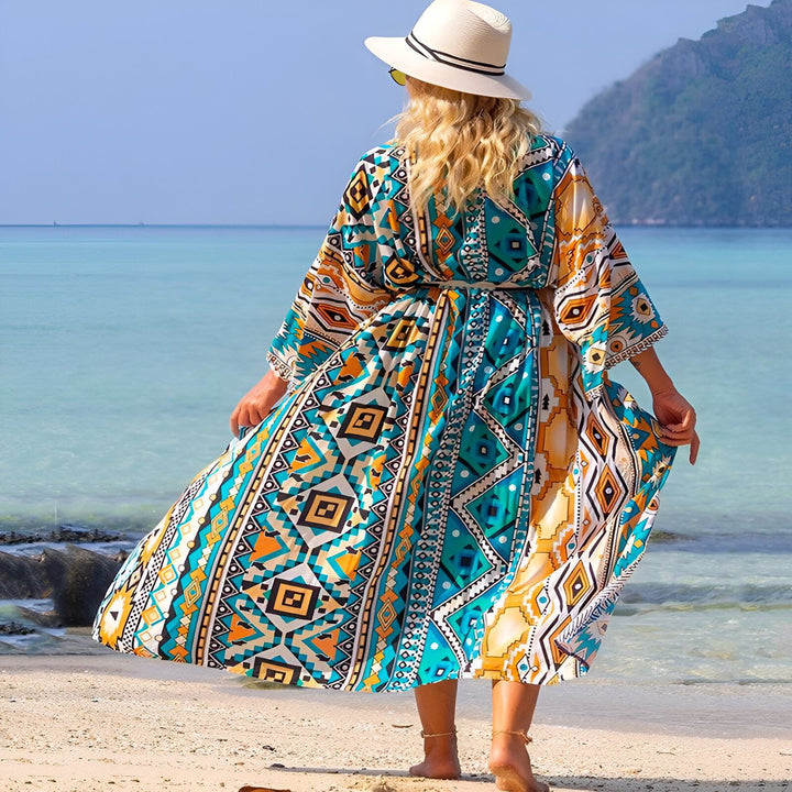 Femme portant un kimono coloré à motifs géométriques sur une plage ensoleillée. Vêtement de plage idéal pour l'été. Kimonos de notre collection disponible en ligne.