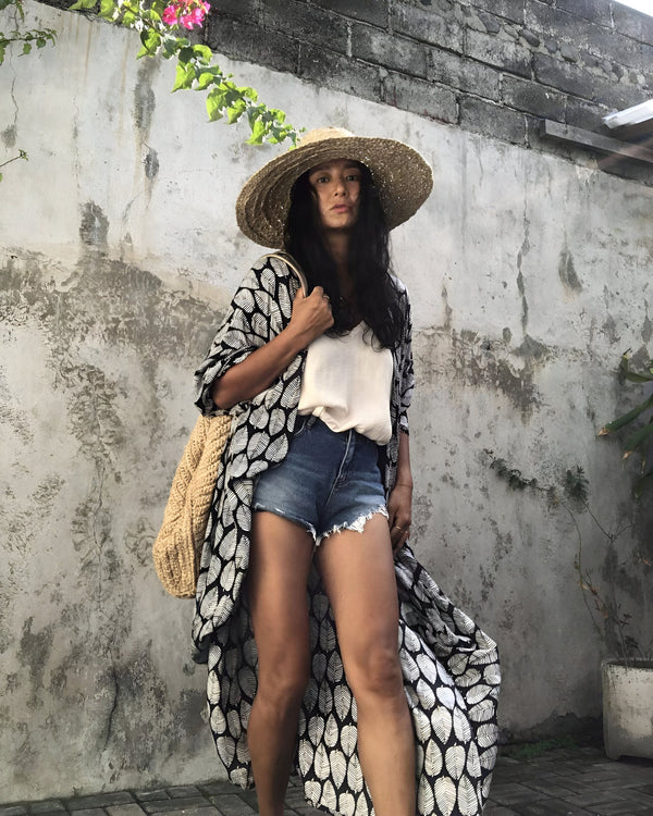 Femme portant un kimono à motifs, un chapeau de paille et un sac tressé. Vêtements d'été, style décontracté. Kimonos élégants disponibles à l'achat.