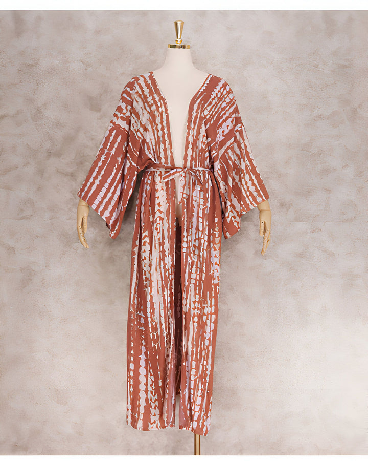 Kimono long en coton imprimé tie and dye, présenté sur un mannequin. Le kimono est marron avec des rayures blanches verticales. Il a une ceinture à nouer et des manches larges.