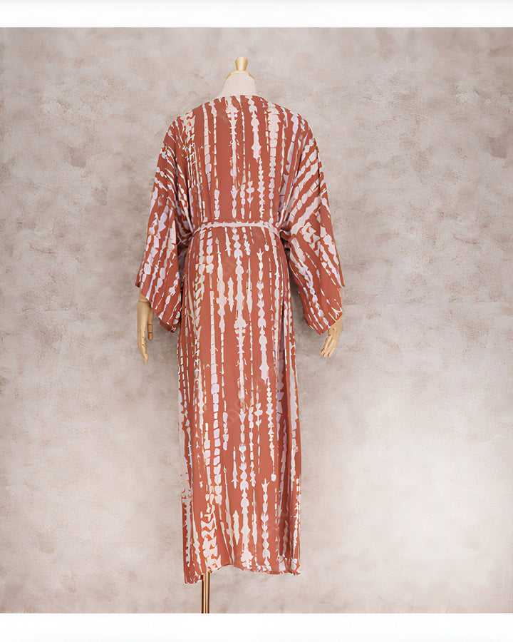 Vue arrière d'une longue robe de style kimono marron avec des rayures blanches, portée par un mannequin. La robe est cintrée à la taille avec une ceinture assortie. Idéal pour un look décontracté et élégant.
