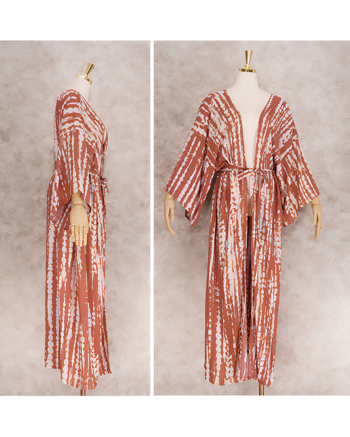 Kimono long marron avec motifs tie-dye blancs, manches larges, noué à la taille. Porté sur un mannequin. Détail de la texture du tissu et de la coupe ample. Idéal pour l'été ou comme vêtement de détente.