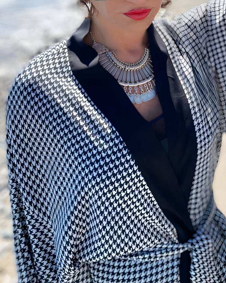 Femme portant un kimono à motifs pied-de-poule noir et blanc. Détails : col noir, collier argenté. Kimonos élégants et confortables en vente.
