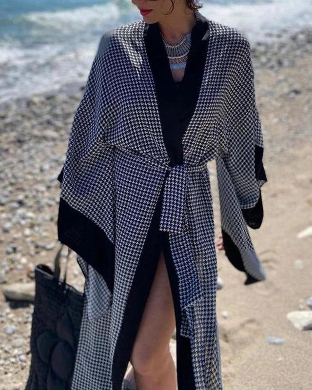 Femme portant un kimono à motif pied-de-poule sur la plage. Élégance et confort avec ce vêtement d'extérieur parfait pour la saison. Découvrez notre collection de kimonos uniques.