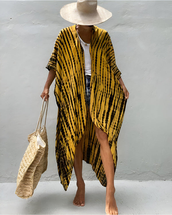 Femme portant un kimono jaune et noir à rayures, chapeau de paille, et sac en fibres naturelles. Kimono de notre boutique en ligne.