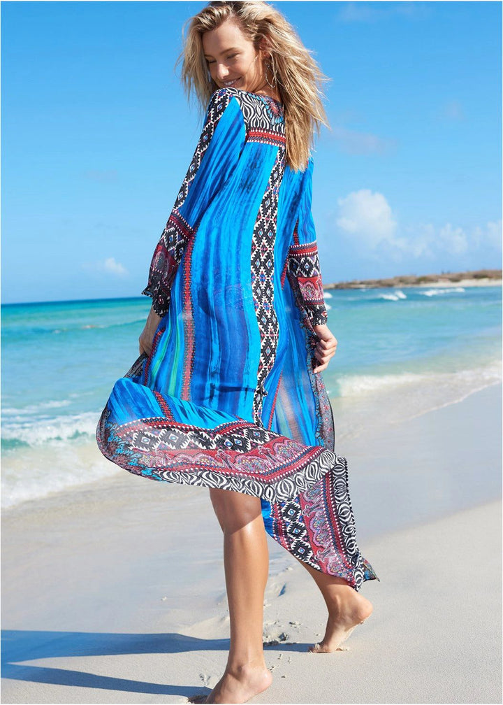 Femme souriante portant un kimono bleu imprimé sur une plage ensoleillée. Vêtements de plage élégants. Collection de kimonos pour femmes.