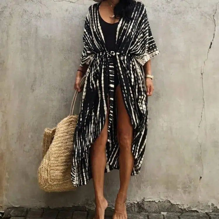 Femme portant un kimono long noir et blanc avec une ceinture et un sac en paille. Kimonos pour femmes, vêtements d'été élégants.