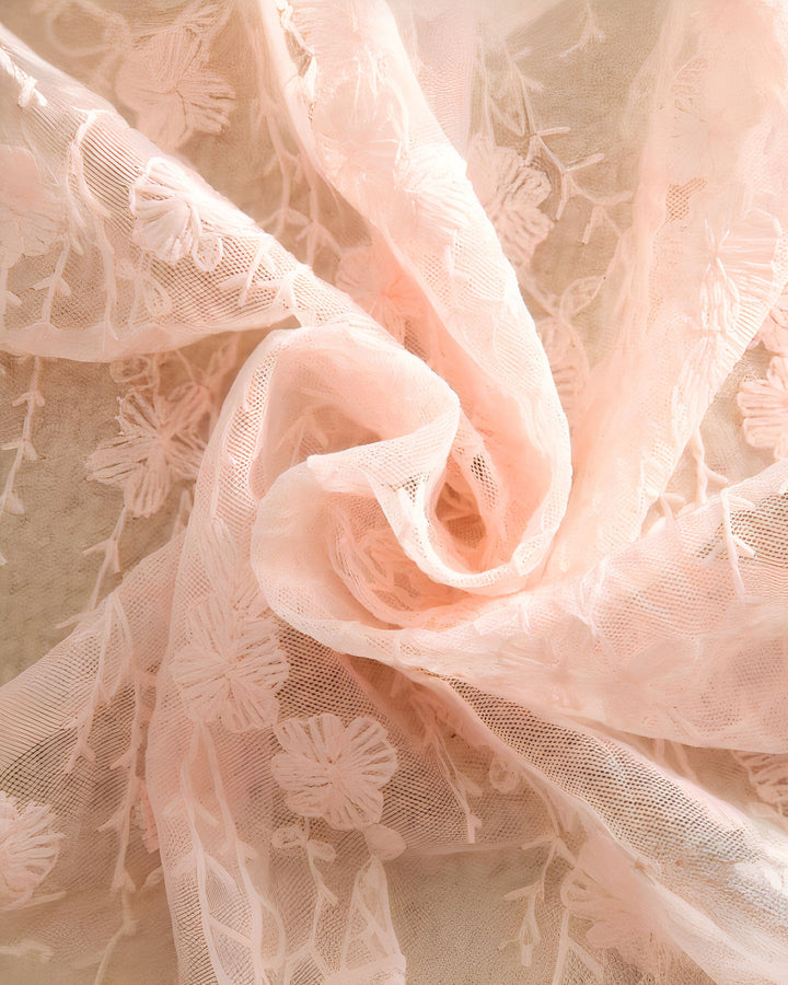 Détail de tissu en dentelle rose pâle avec motifs floraux. Idéal pour un kimono léger et élégant. Découvrez notre collection.