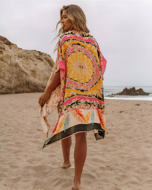 Femme blonde portant un kimono coloré sur la plage. Kimono à motifs floraux et géométriques, parfait pour l'été. Découvrez notre collection de kimonos uniques.