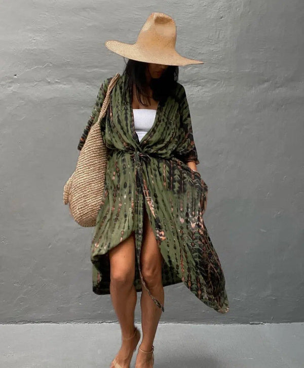 Kimono vert tie-dye porté par une femme avec un chapeau de paille et un sac en osier. Élégance décontractée pour toutes occasions. Découvrez notre collection de kimonos uniques.