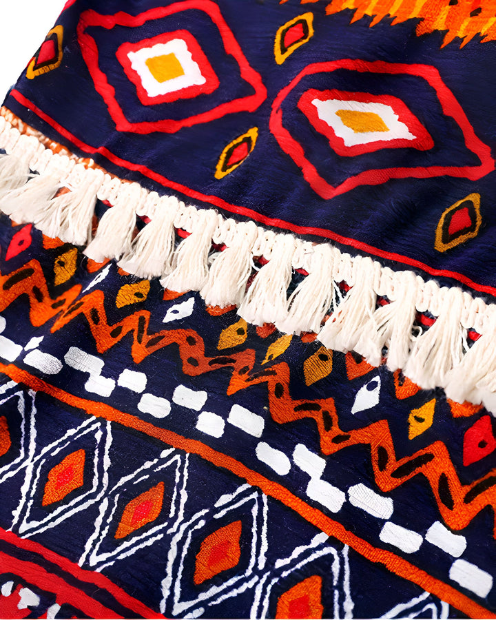 Détail d'un kimono avec motifs géométriques ethniques bleus, rouges, oranges et blancs. Franges décoratives blanches. Motifs losanges et carrés. Idéal pour un style bohème et original.