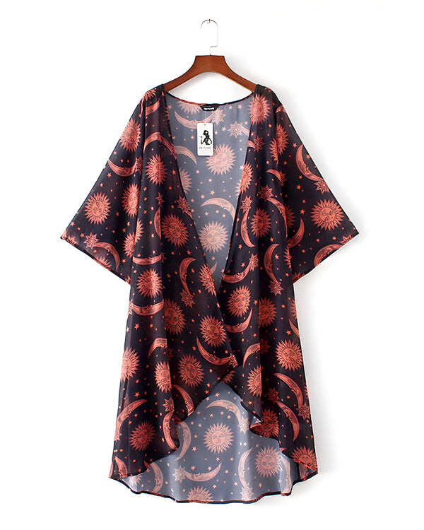 Kimono noir et orange à motifs de soleils, lunes et étoiles suspendu sur un cintre. Vêtement léger, parfait pour l'été. Notre collection de kimonos uniques.