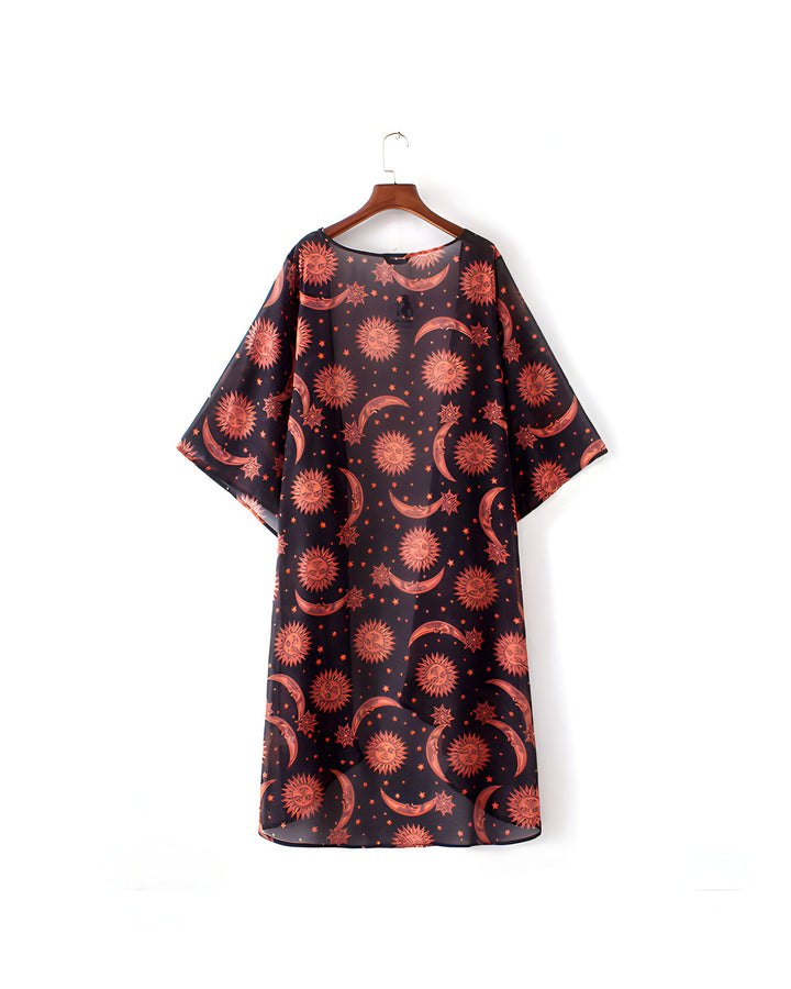Kimono noir transparent avec motifs de lunes et de soleils oranges, suspendu à un cintre. Vêtement ample et léger, idéal pour un style bohème ou estival. Disponible dans notre collection de kimonos.