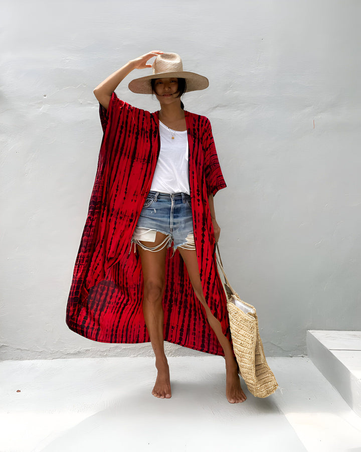 Femme élégante en kimono rouge, short en jean, chapeau de paille et sac en raphia. Look décontracté et tendance pour l'été, ambiance vacances.