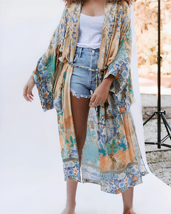 Femme portant un kimono à motifs floraux sur un débardeur blanc et un short en jean délavé. Style bohème et estival.