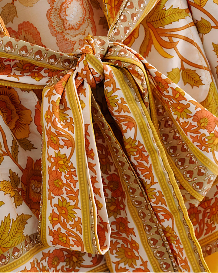 Détail d'un kimono avec un motif floral orange et doré, noué à la taille. Vêtements traditionnels japonais en vente.