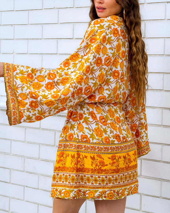 Kimono court fleuri orange et blanc, manches évasées. Vêtement bohème chic idéal pour un look estival. Collection de kimonos uniques.